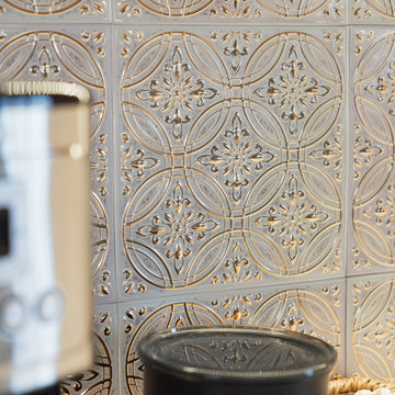 Pastel painted gold metal tile backsplash behind a sunlit kitchen counter, a smooth aluminum surface that wipes clean