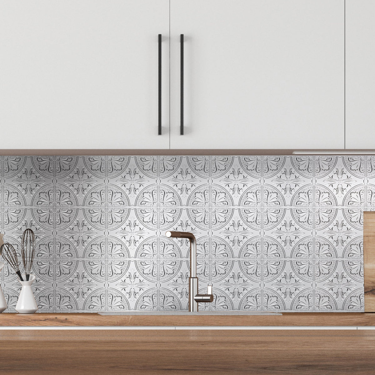 Silver Fleur metal tiles covering a kitchen wall from a wood countertop up to white upper cabinets, behind a faucet and a crock of whisks