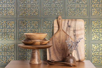Green and gold peel and stick metal tile backsplash behind a farmhouse kitchen counter with wooden boards and bowls, showing the durable embossed aluminum finish.
